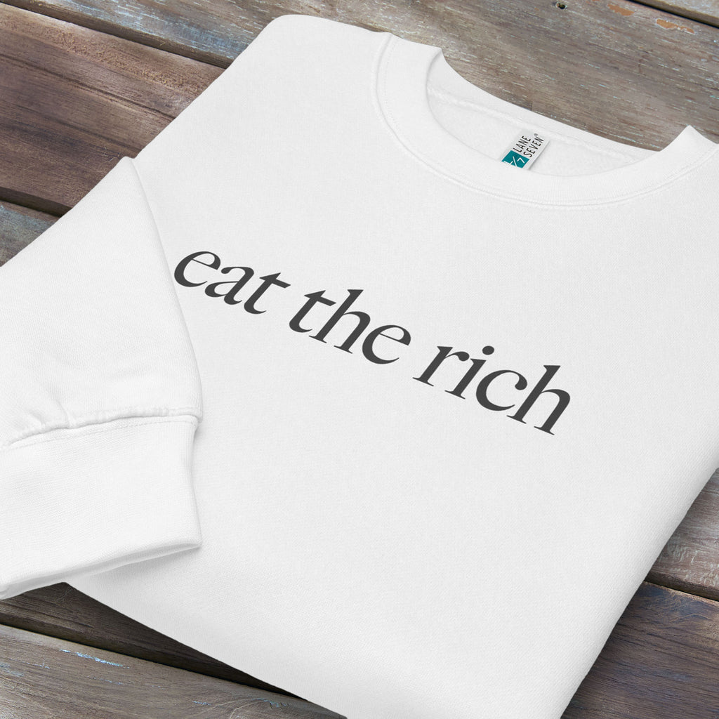 Folded white sweatshirt with minimalist dark grey text reading “eat the rich."