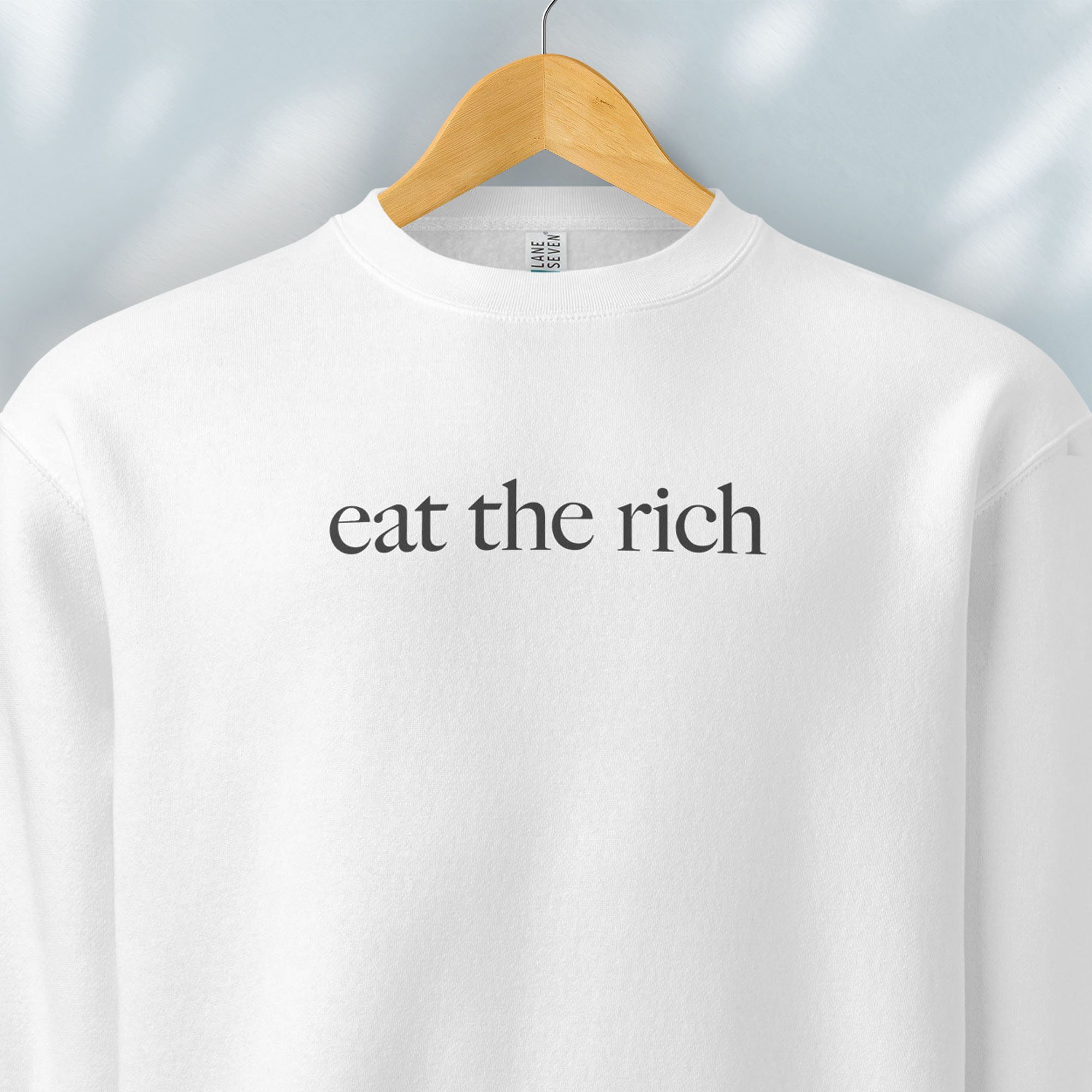 Hanging white sweatshirt with minimalist dark grey text reading “eat the rich."
