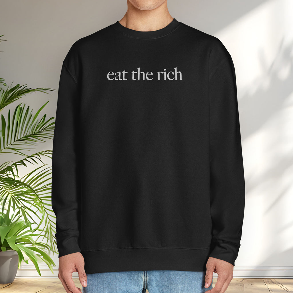 Male model wearing black sweatshirt with minimalist light grey text reading “eat the rich."