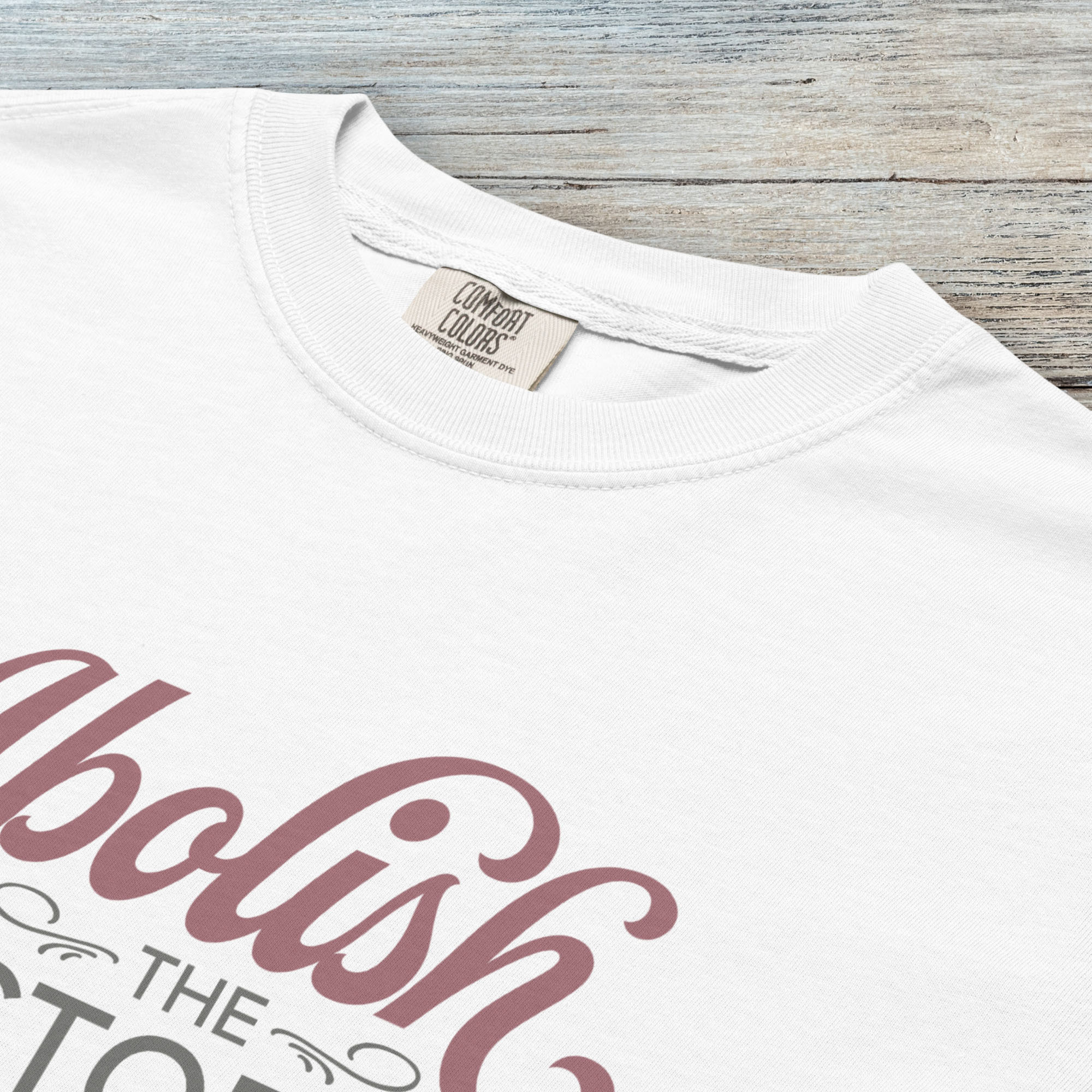 Closeup detail of white t-shirt with stylized text reading “Abolish the Electoral College” in muted red and gray, minimalist pro-democracy design.
