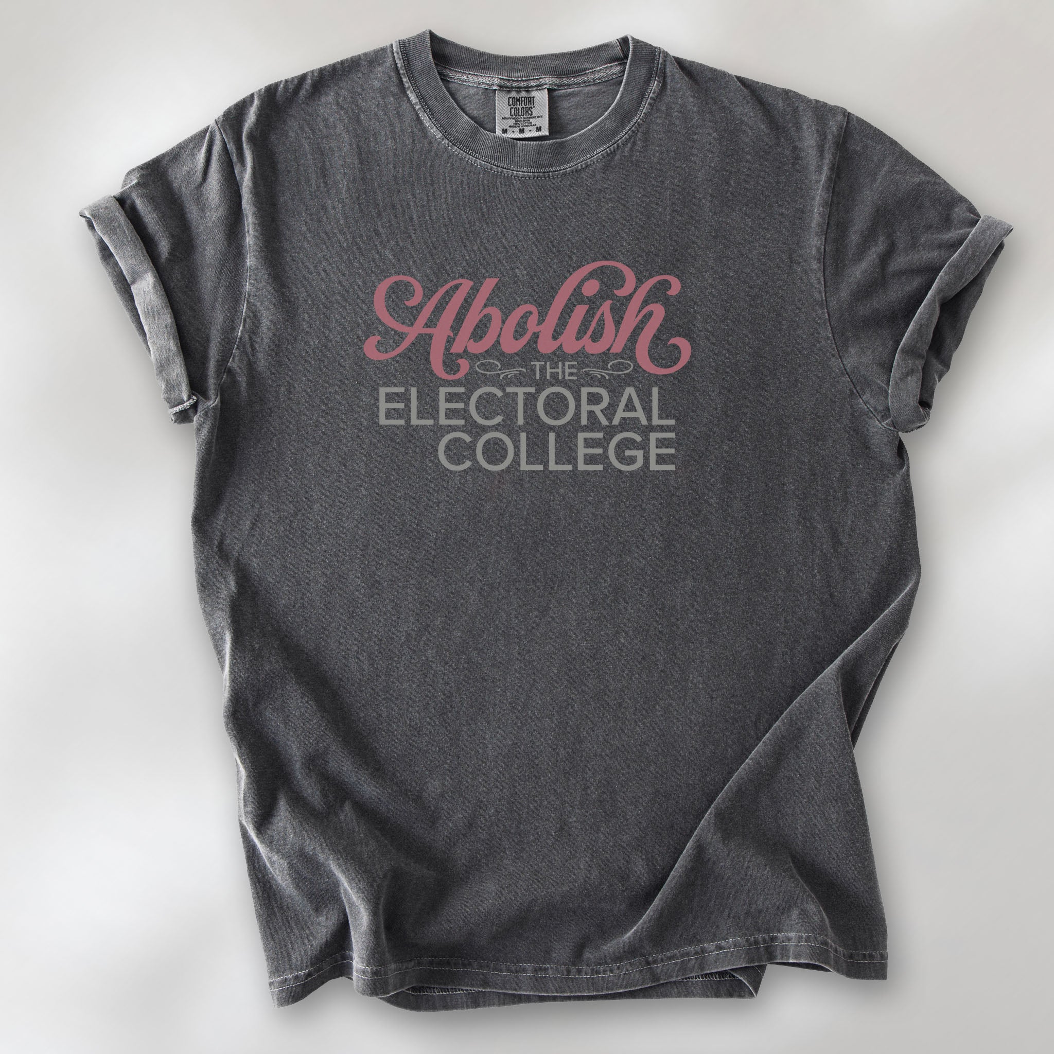 Pepper t-shirt with stylized text reading “Abolish the Electoral College” in muted red and gray, minimalist pro-democracy design.
