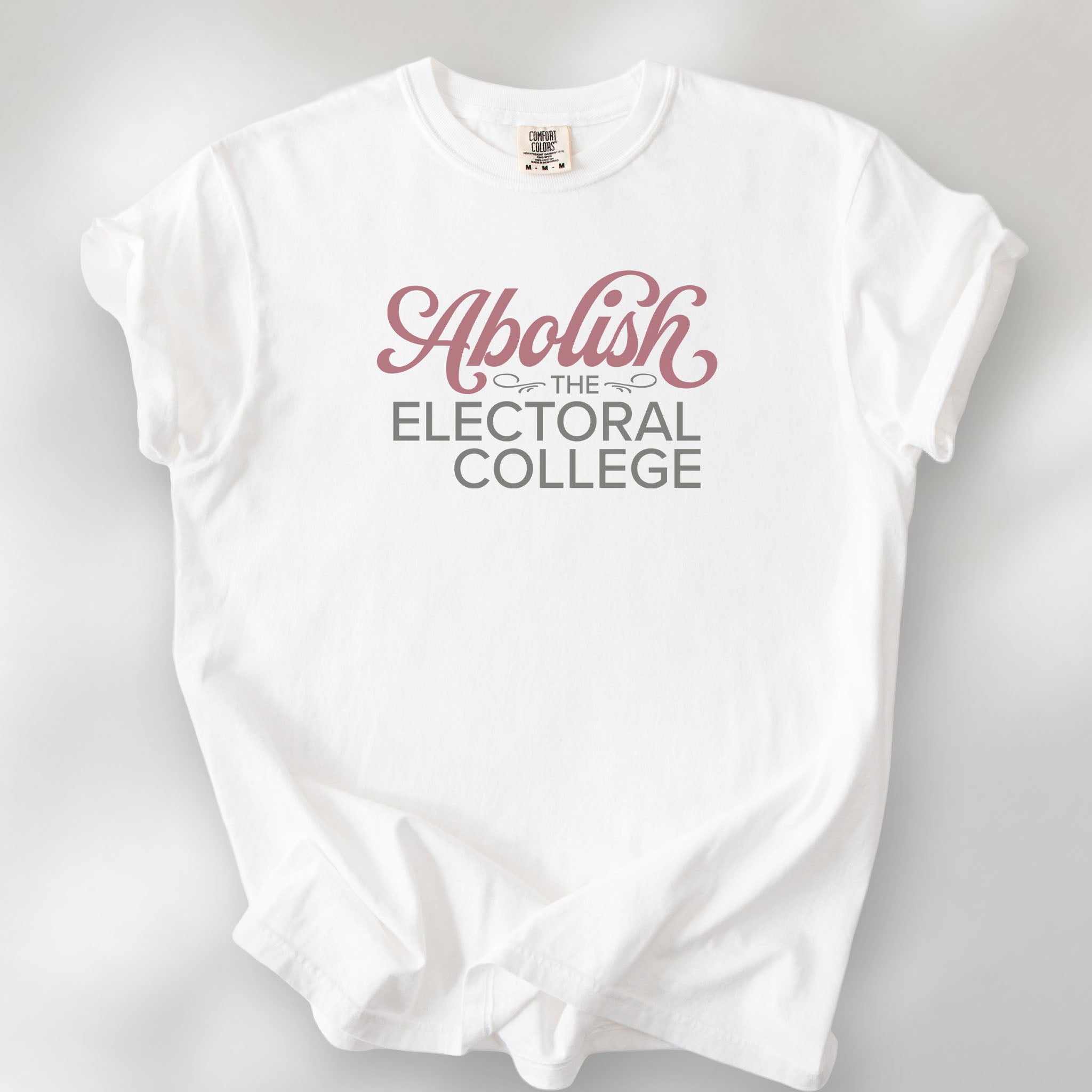 White t-shirt with stylized text reading “Abolish the Electoral College” in muted red and gray, minimalist pro-democracy design.