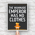 Protest sign reading “The Wannabe Emperor Has No Clothes” with cartoon illustration of an orange baby with weird yellow hair dressed only in his underwear, looking much like Donald Trump.
