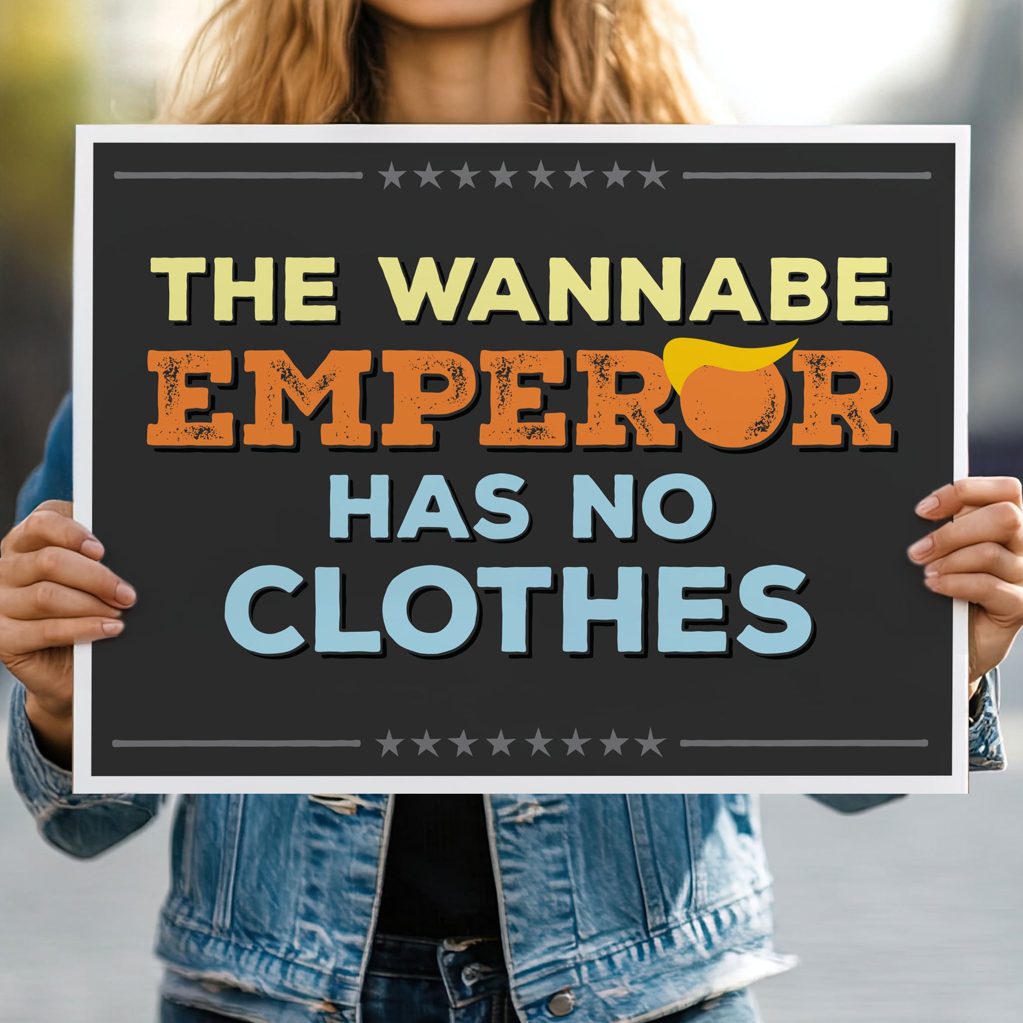 Person holding protest sign reading “The Wannabe Emperor Has No Clothes” with bold lettering and a stylized yellow hair graphic.