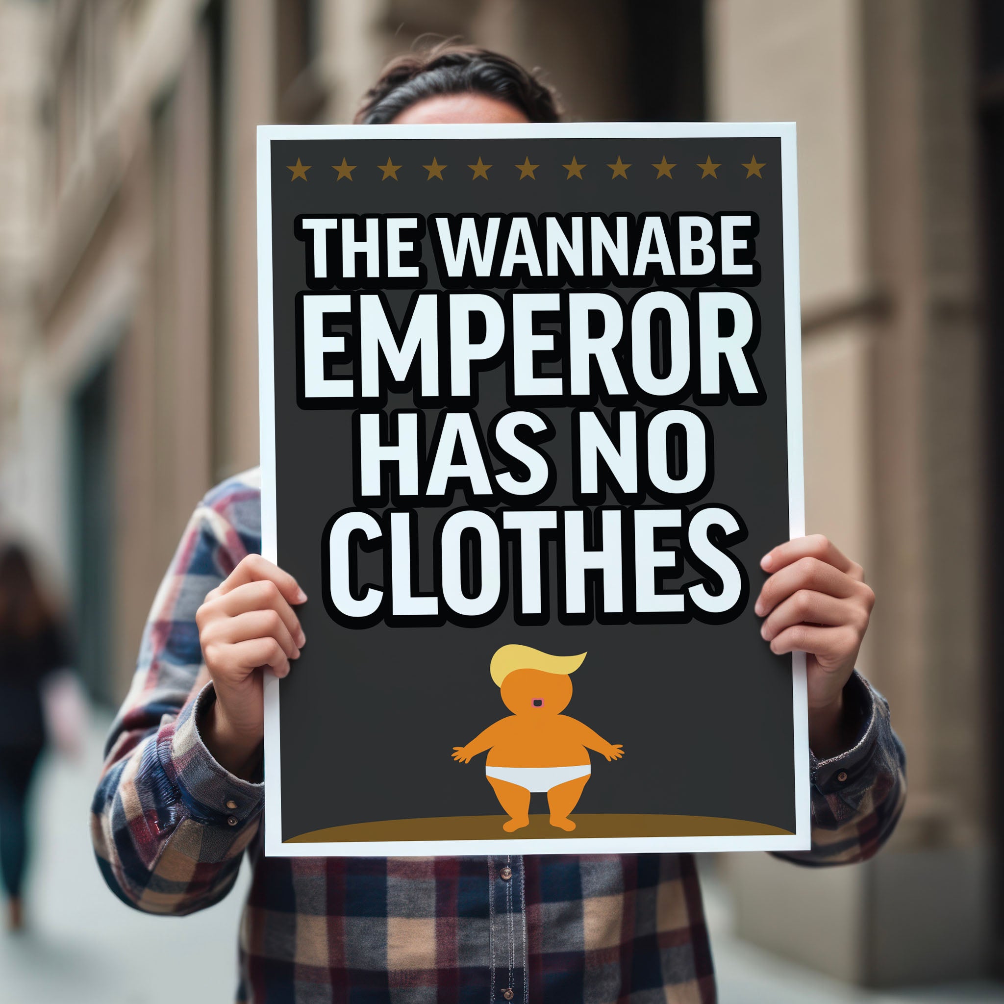 Person holding protest sign reading “The Wannabe Emperor Has No Clothes” with cartoon illustration of an orange baby with weird yellow hair dressed only in his underwear, looking much like Donald Trump.