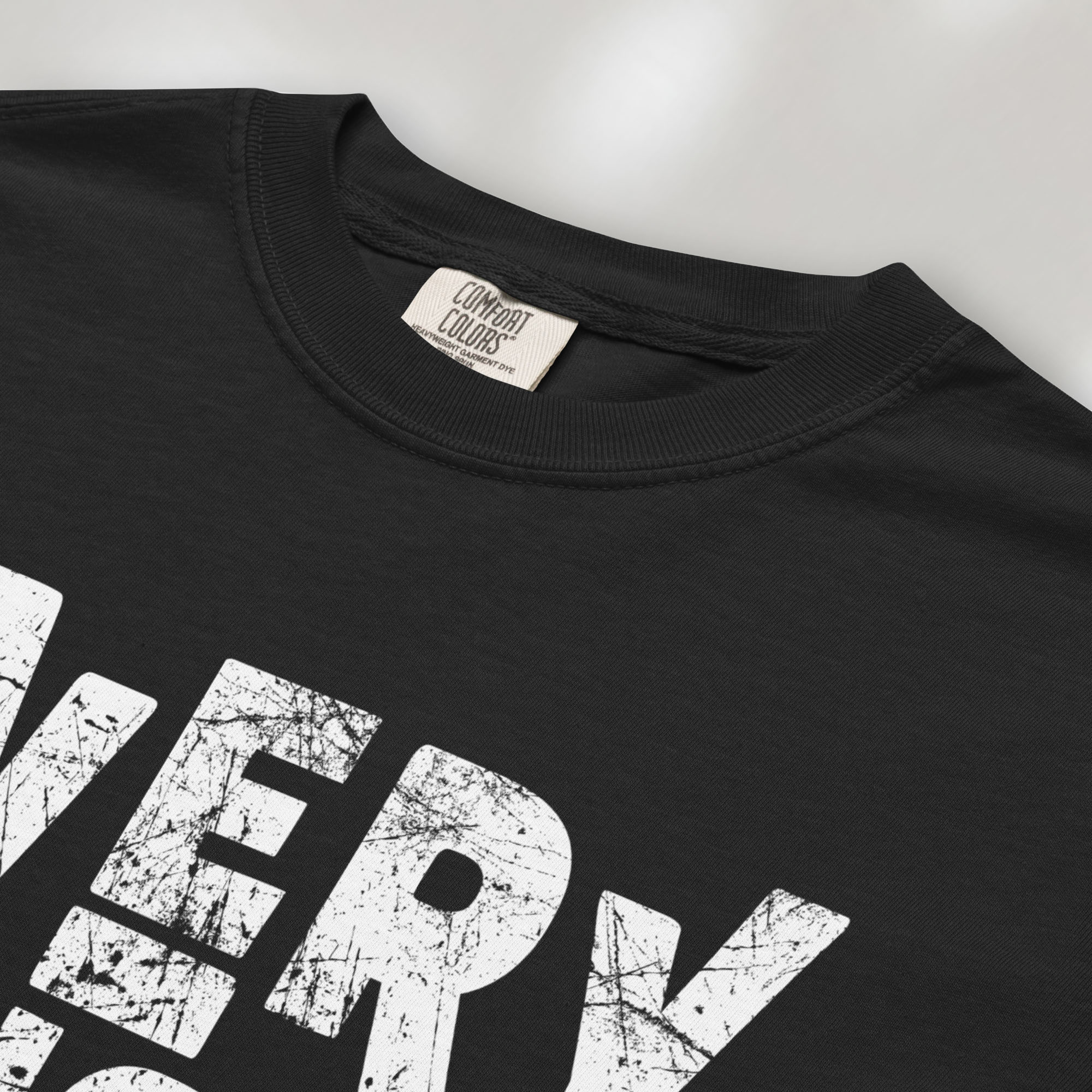 Closeup detail of black t-shirt featuring distressed block typography reading "Everything Is Political" in a bold minimalist design.