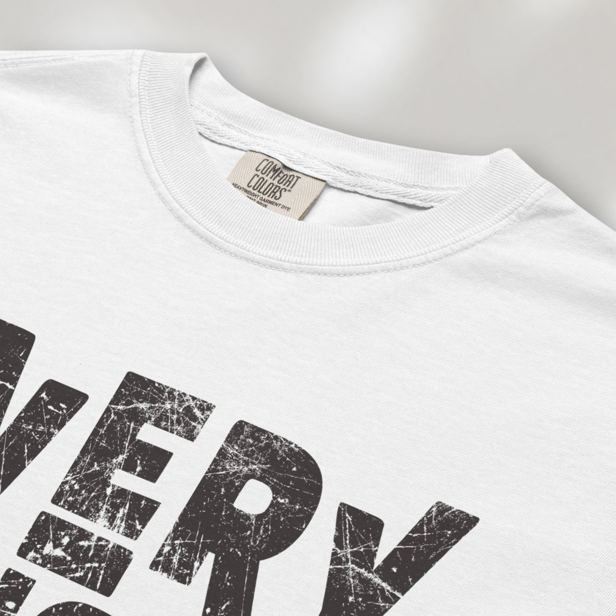 Closeup detail of white t-shirt featuring distressed block typography reading "Everything Is Political" in a bold minimalist design.
