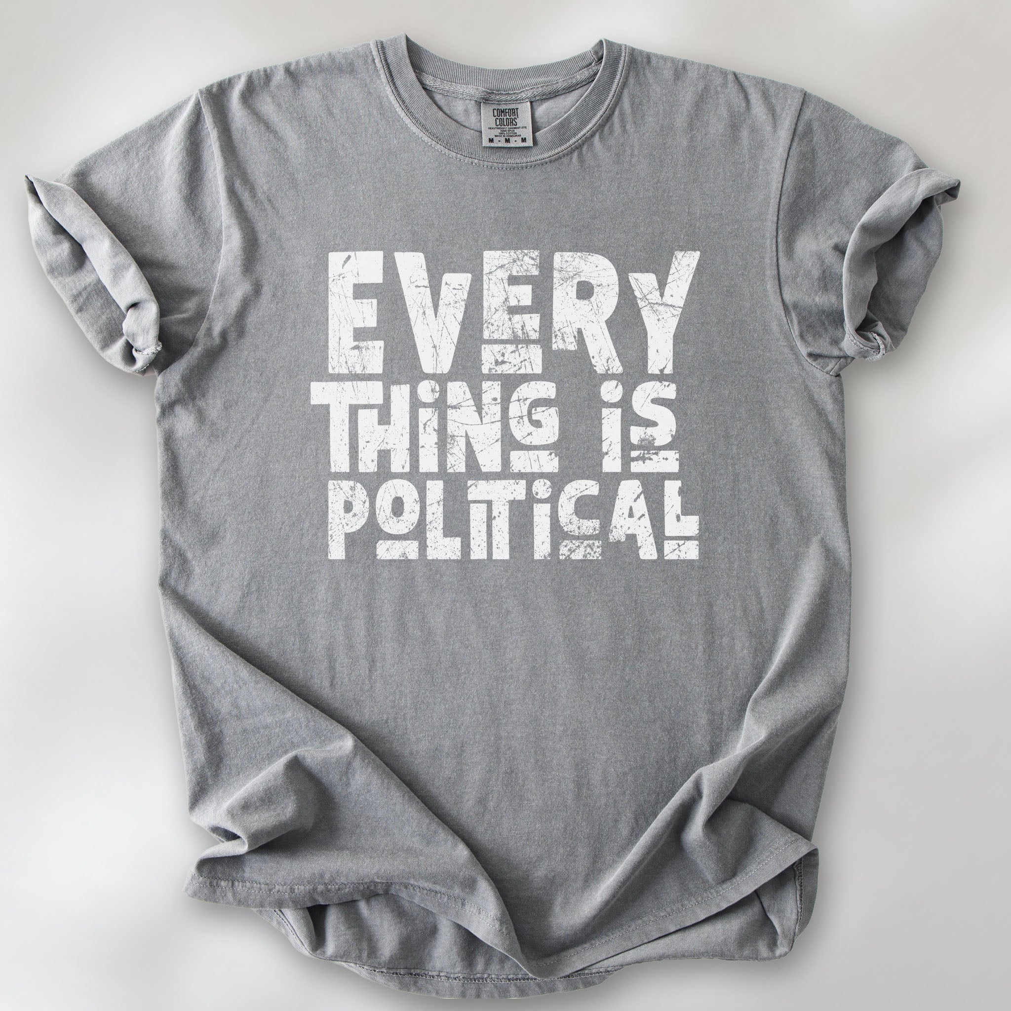 Grey t-shirt featuring distressed block typography reading "Everything Is Political" in a bold minimalist design.