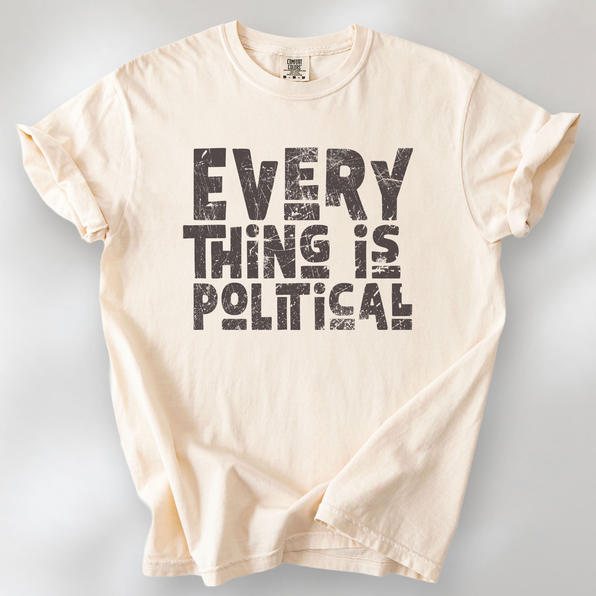 Ivory t-shirt featuring distressed block typography reading "Everything Is Political" in a bold minimalist design.