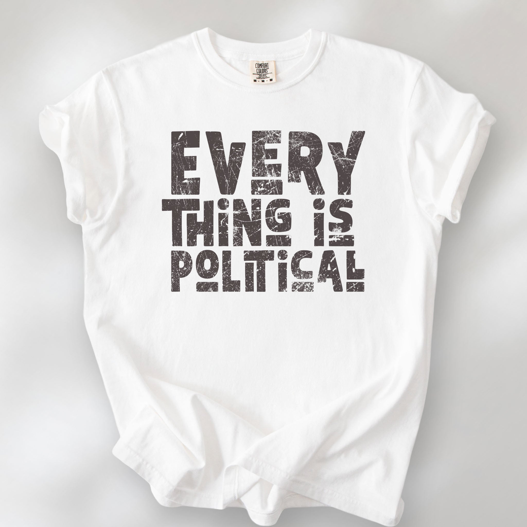 White t-shirt featuring distressed block typography reading "Everything Is Political" in a bold minimalist design.