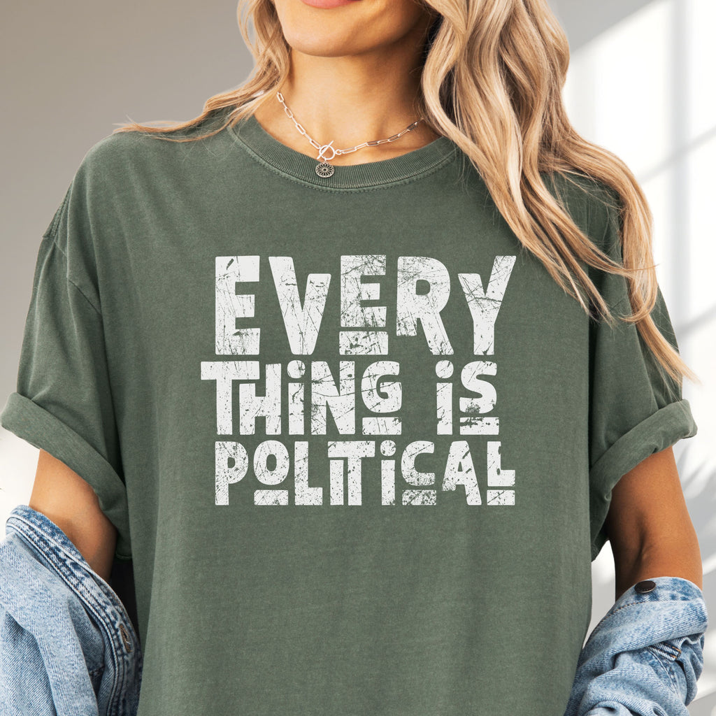 Female model wearing oversized moss t-shirt featuring distressed block typography reading "Everything Is Political" in a bold minimalist design.