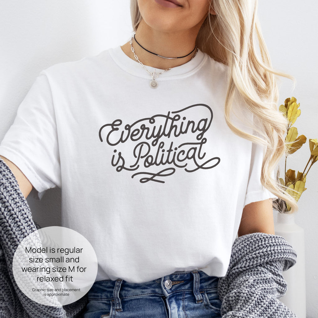 Female model wearing white minimalist script everything is political activist shirt. Includes size and fit information for the model who is regular size small, and wearing a size M shirt for a relaxed fit.