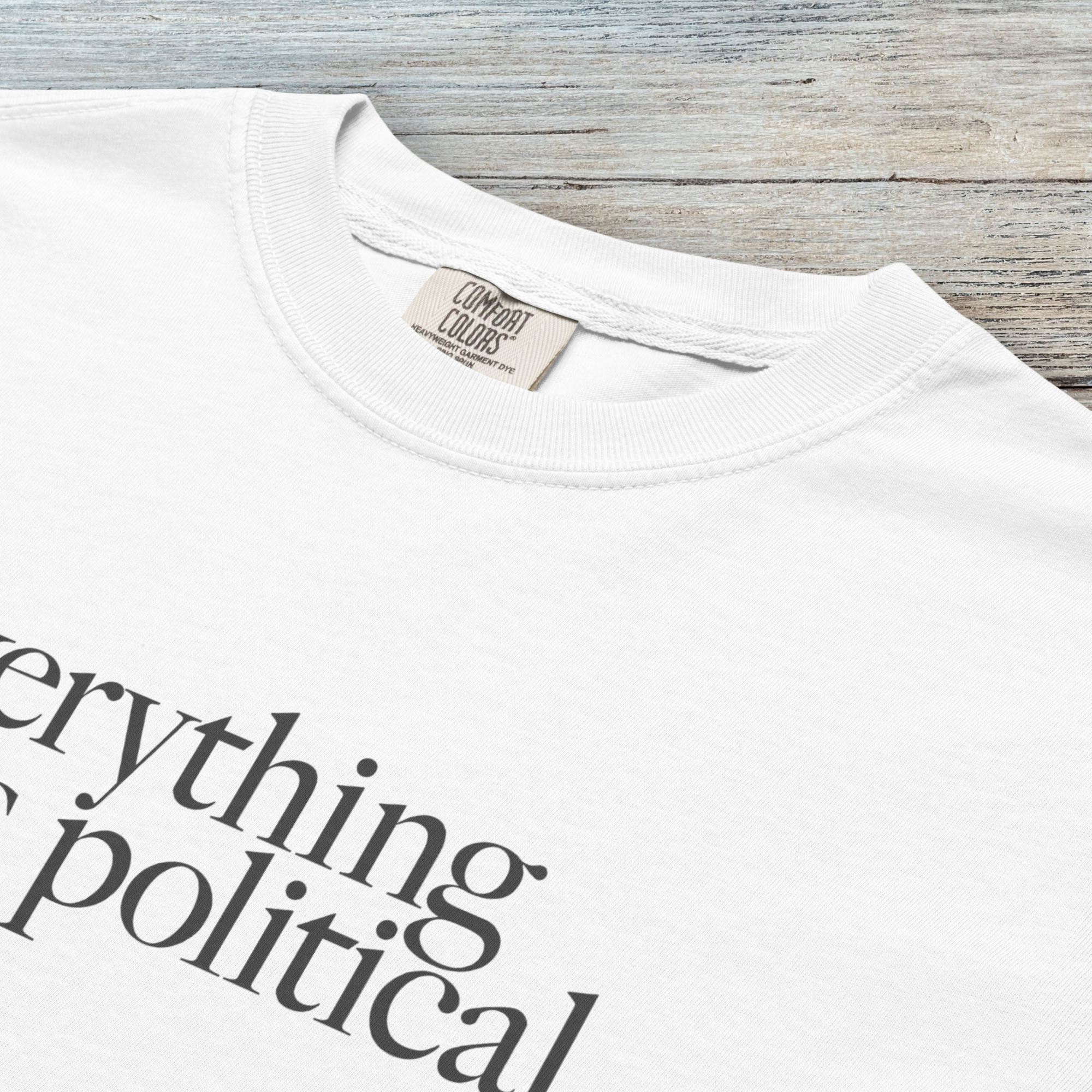 Closeup detail of white unisex t-shirt with minimalist serif gray text reading “everything is political."