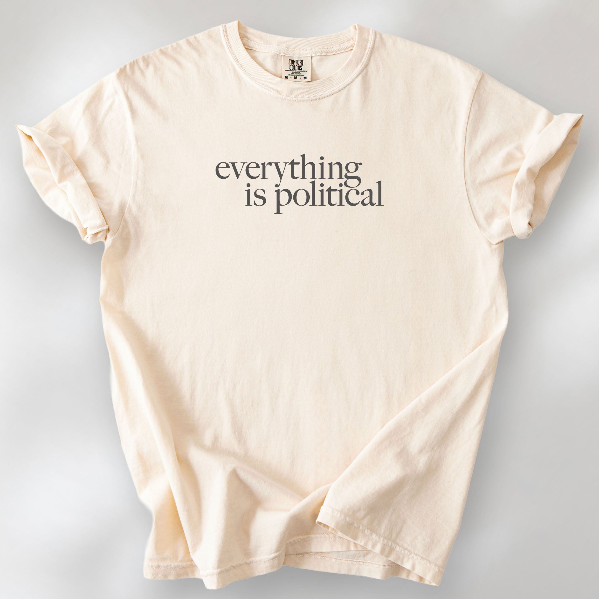 Ivory unisex t-shirt with minimalist serif gray text reading “everything is political."