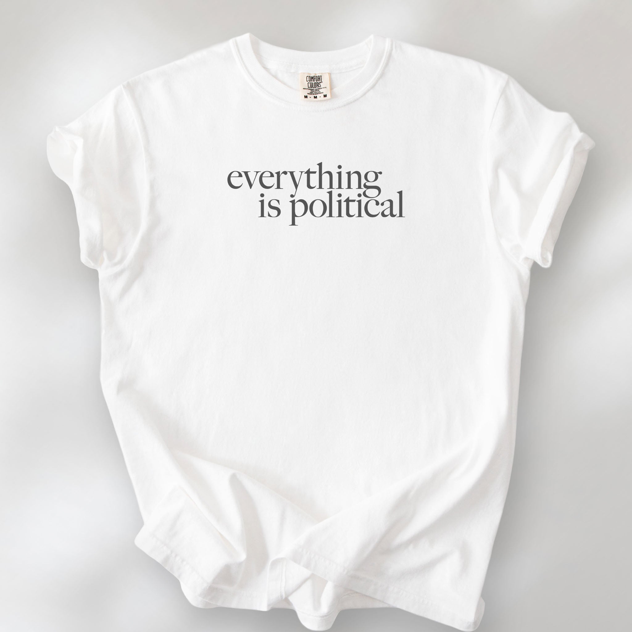 White unisex t-shirt with minimalist serif gray text reading “everything is political."