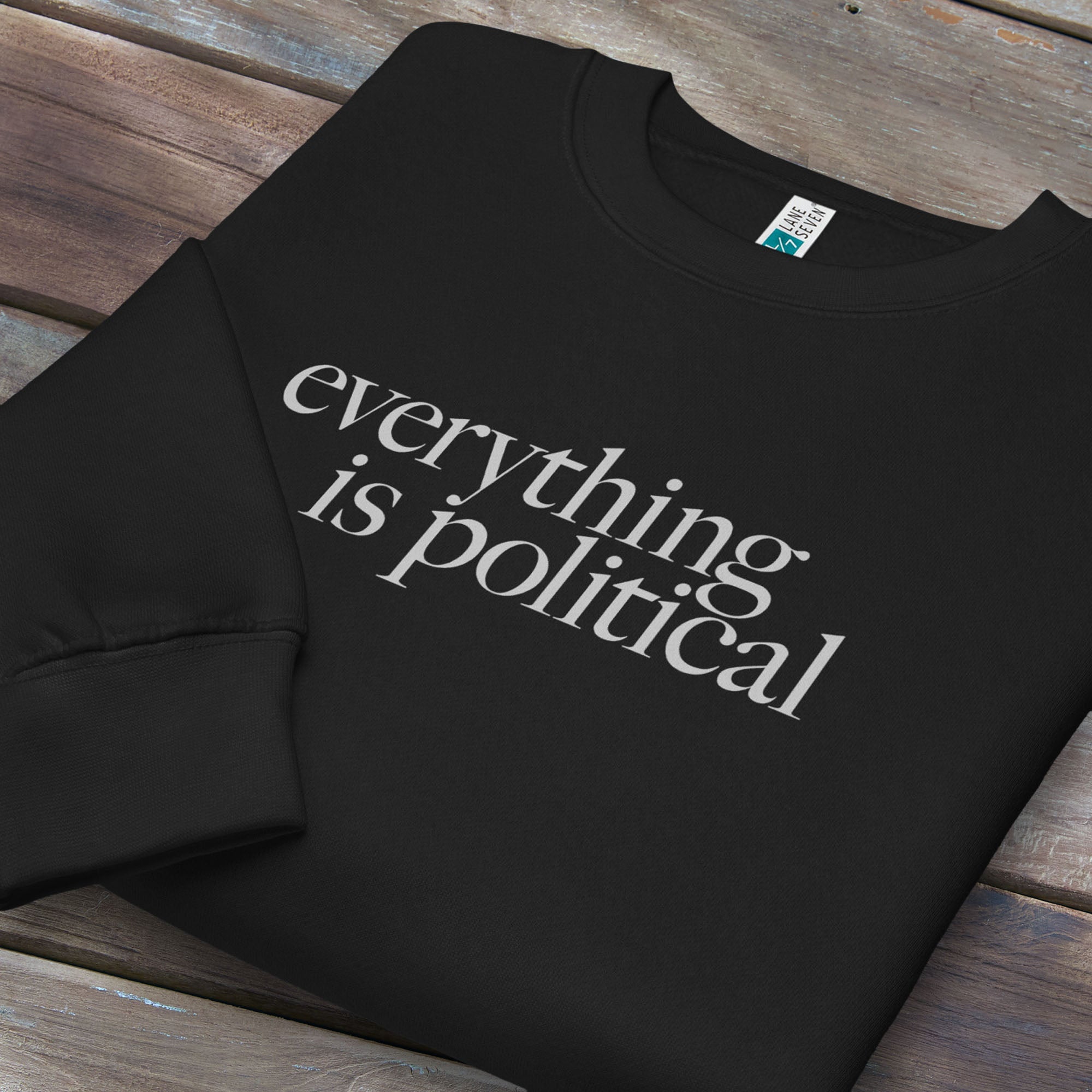 Folded black sweatshirt with minimalist serif gray text reading “everything is political."