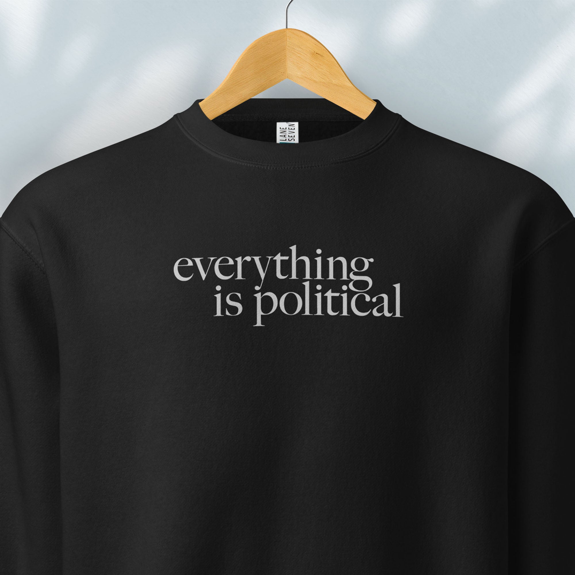 Hanging black sweatshirt with minimalist serif gray text reading “everything is political."