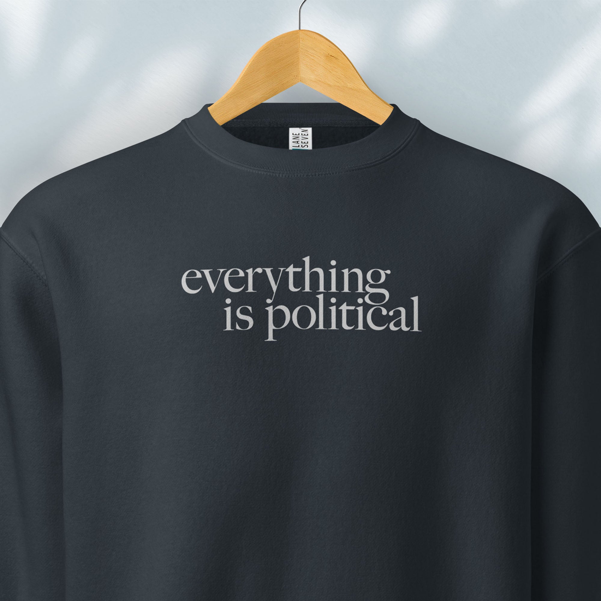 Hanging navy sweatshirt with minimalist serif gray text reading “everything is political."