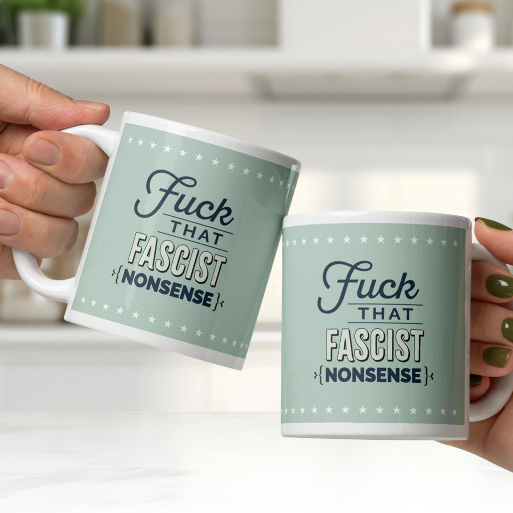 Ceramic mugs with graphic on mint green background and navy styled text block that reads "fuck that fascist nonsense." The mugs are held by two people, clinking them together in a bright white kitchen.