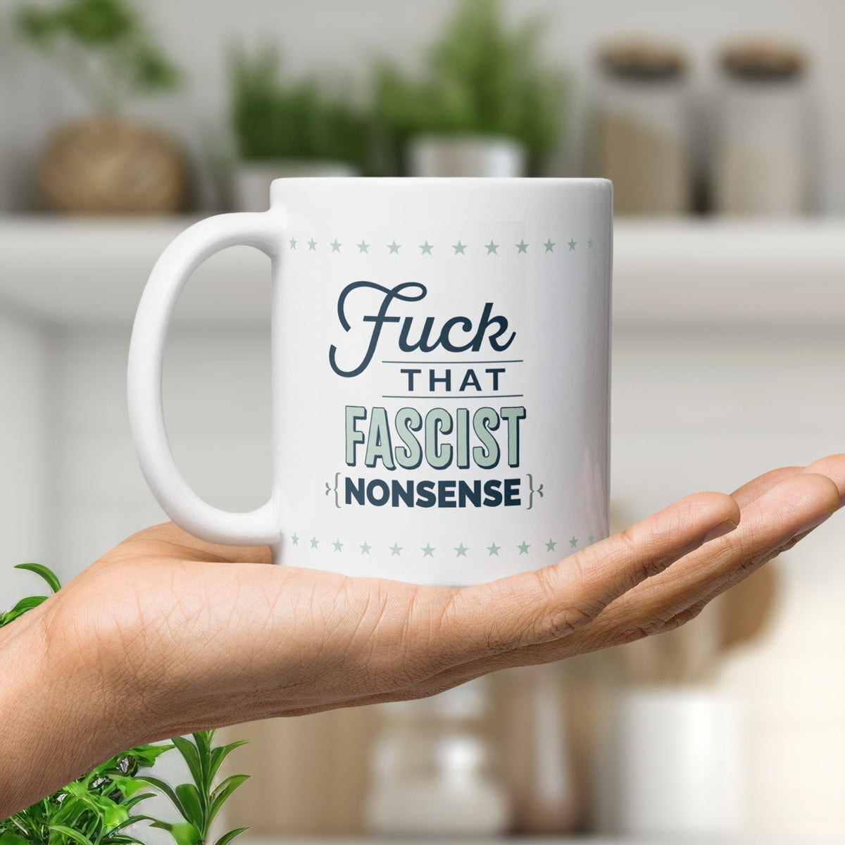 Ceramic mug resting in the palm of a hand. Mug reads "fuck that fascist nonsense" in stylized text block.
