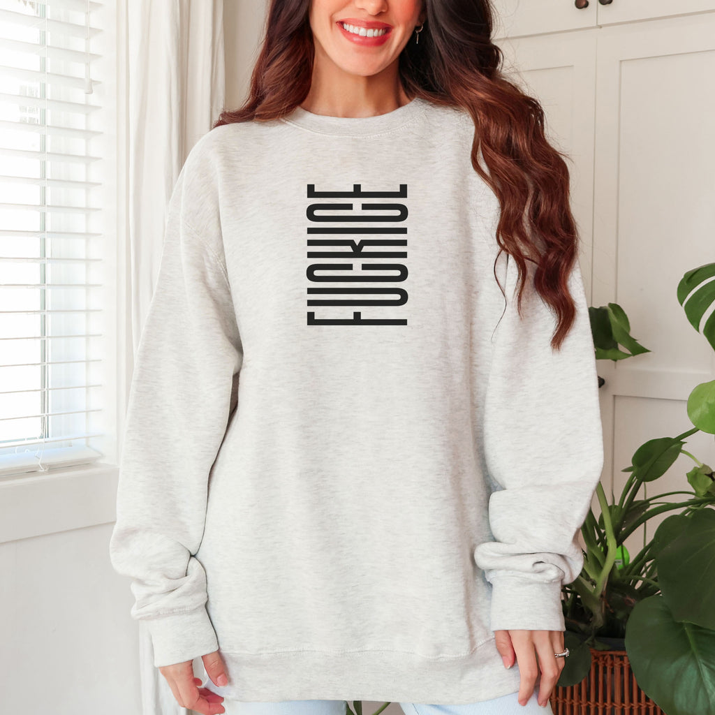 Female model wearing oatmeal unisex sweatshirt with minimalist serif typography reading “FCK ICE,” an anti-ICE political message opposing Immigration and Customs Enforcement abuses and violence.