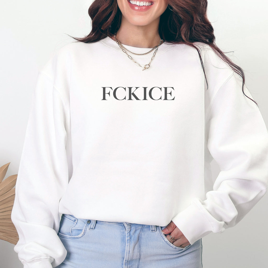 Female model wearing white unisex sweatshirt with minimalist serif typography reading “FCK ICE,” an anti-ICE political message opposing Immigration and Customs Enforcement abuses and violence.