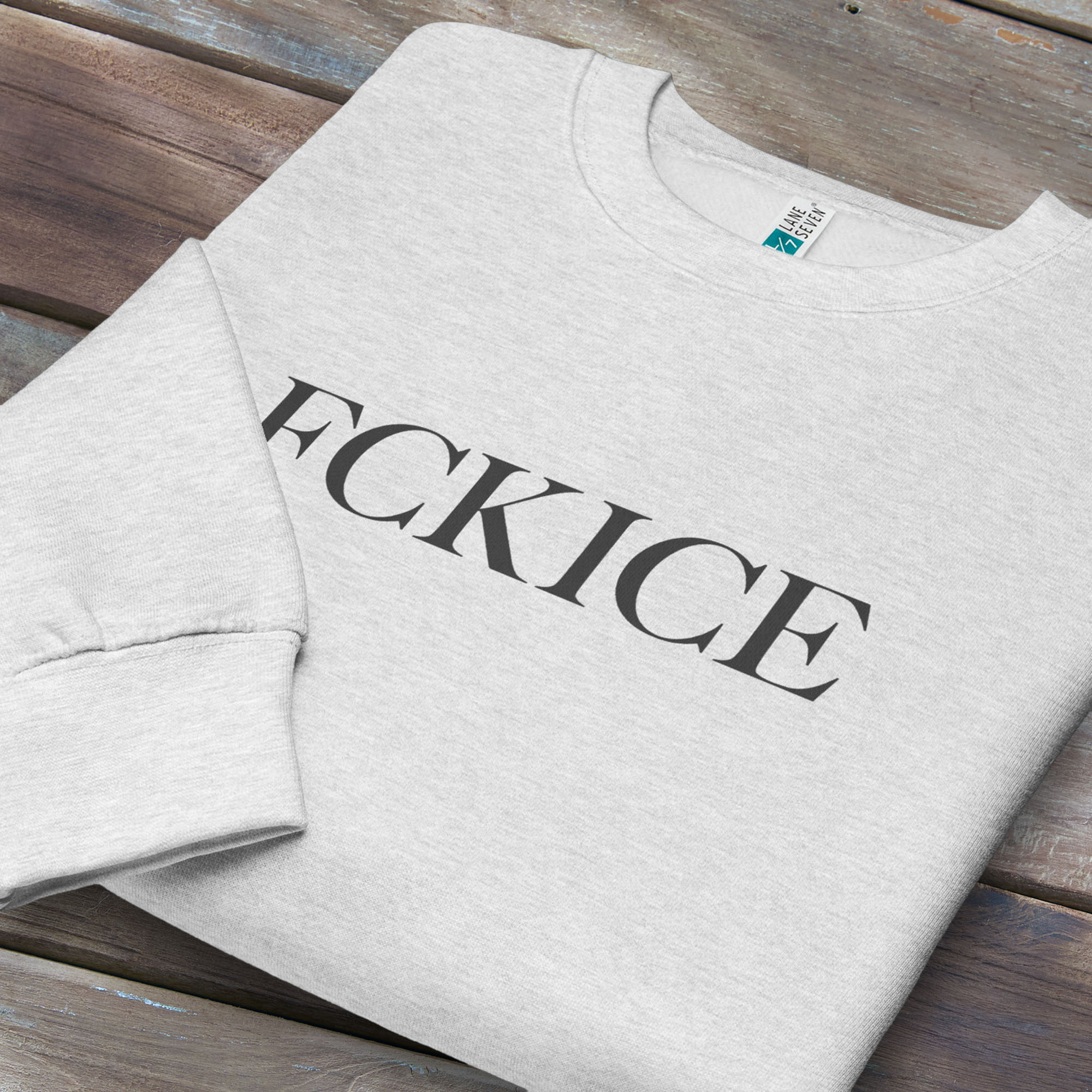 Folded grey sweatshirt with minimalist serif typography reading “FCK ICE,” an anti-ICE political message opposing Immigration and Customs Enforcement abuses and violence.