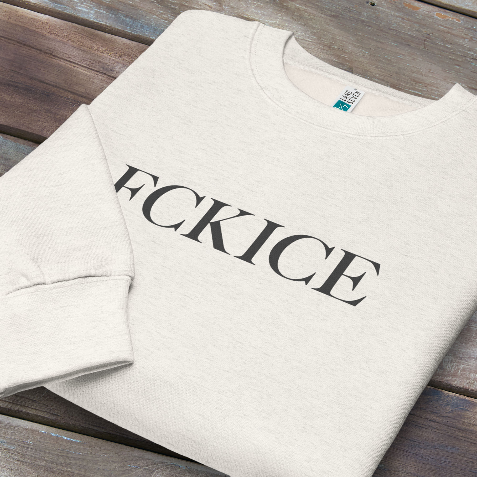 Folded oatmeal sweatshirt with minimalist serif typography reading “FCK ICE,” an anti-ICE political message opposing Immigration and Customs Enforcement abuses and violence.