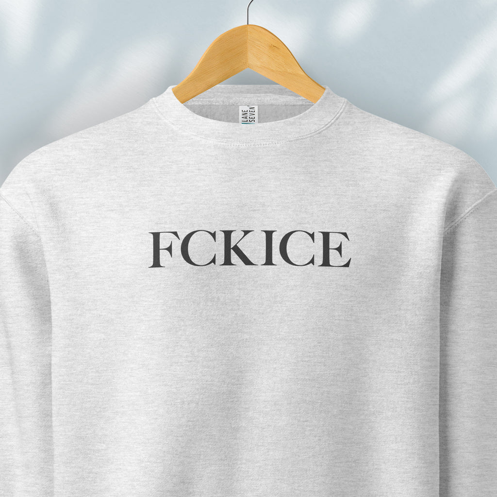 Hanging heather grey sweatshirt with minimalist serif typography reading “FCK ICE,” an anti-ICE political message opposing Immigration and Customs Enforcement abuses and violence.
