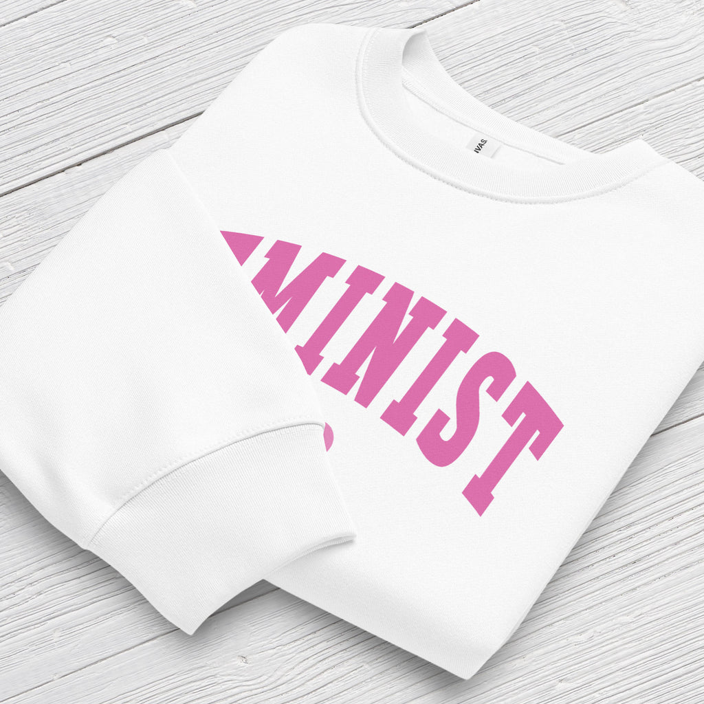 Folded white Bella + Canvas heavyweight sweatshirt with pink text that reads “Feminist A.F.” in a collegiate style, showing closeup of cuffs.