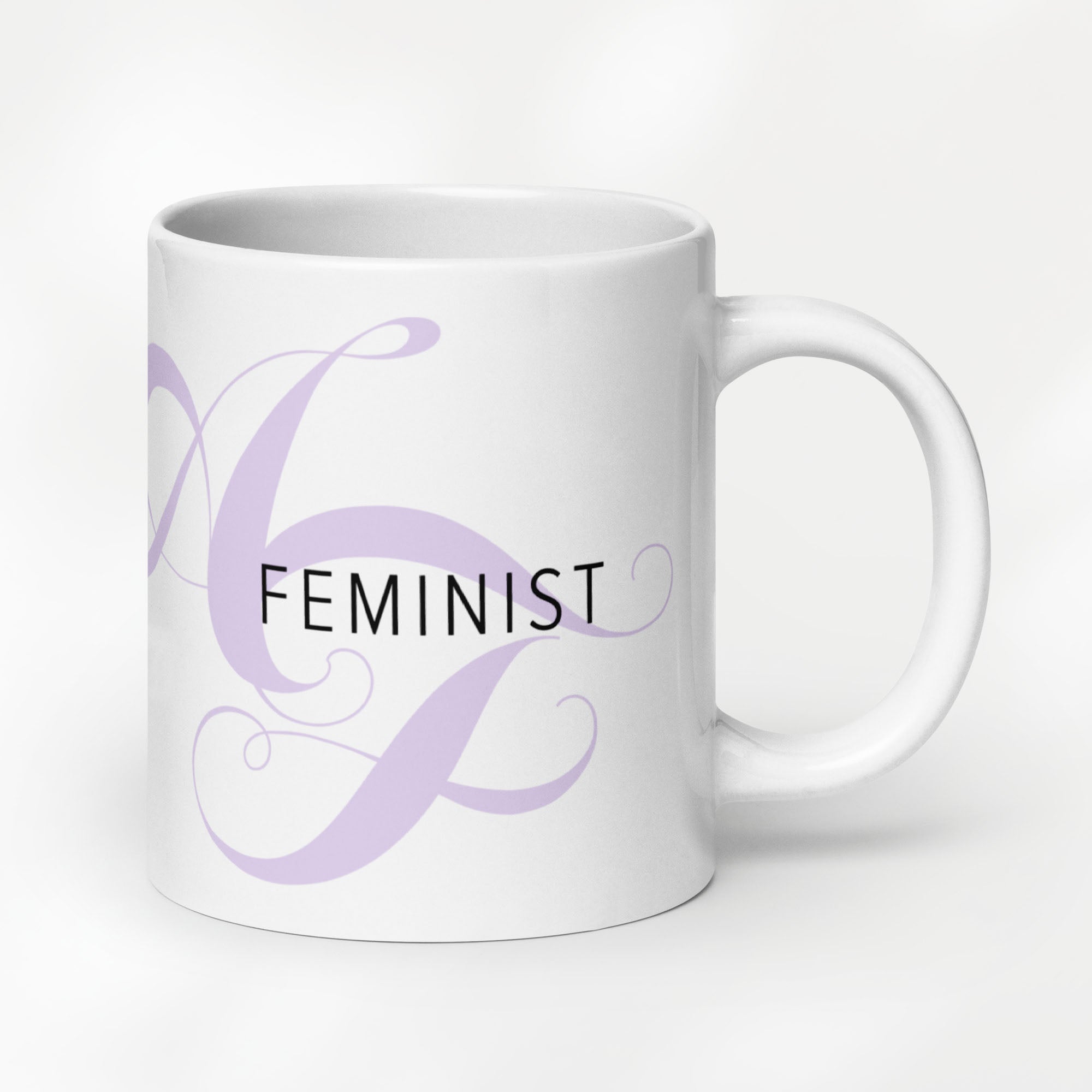 20 ounce white ceramic mug with the word “Feminist” in black text and a subtle lavender script design of the letters A and F in the background.