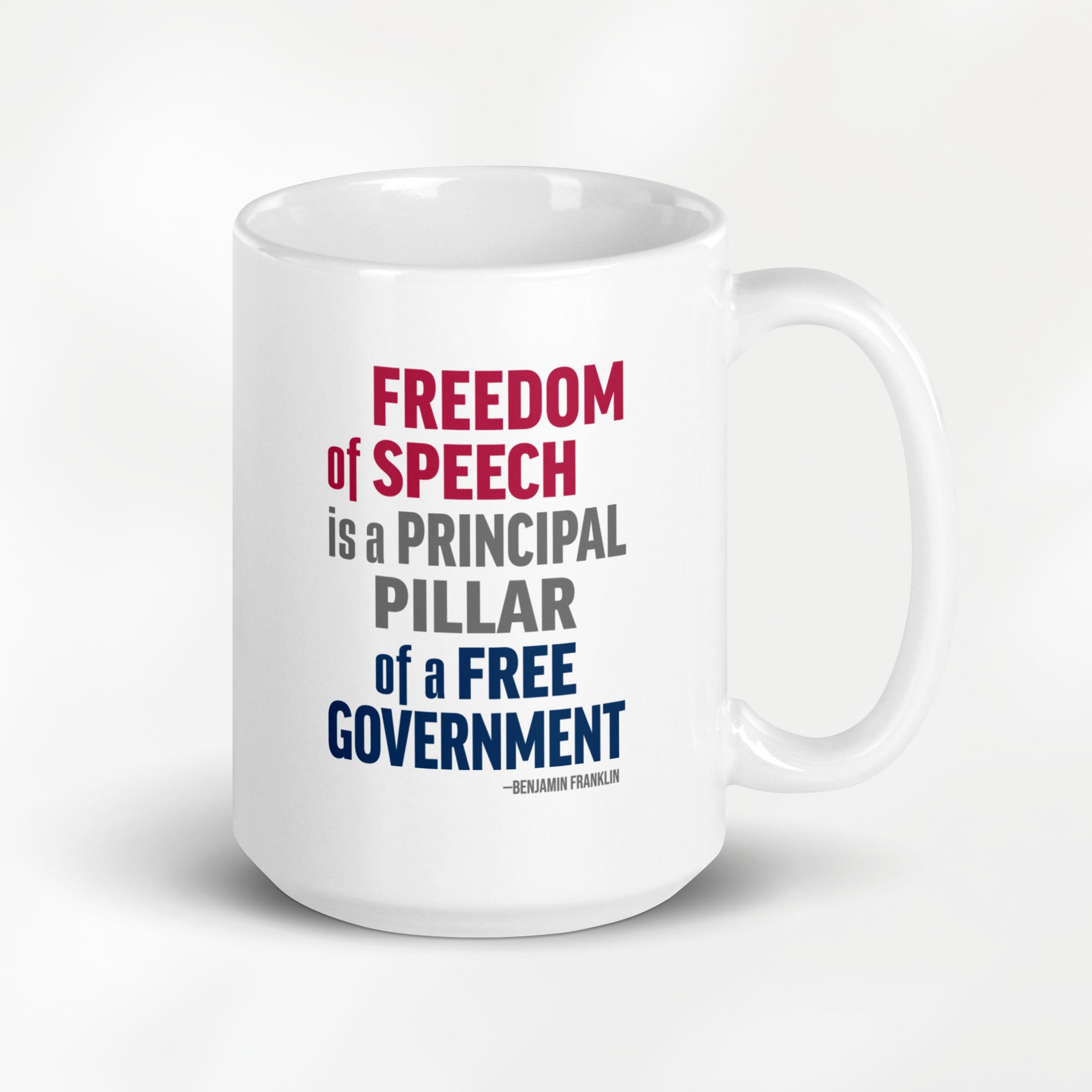 15 ounce white ceramic mug with bold patriotic red, blue, and grey text that reads "Freedom of speech is a principal pillar of a free government. – Ben Franklin." 