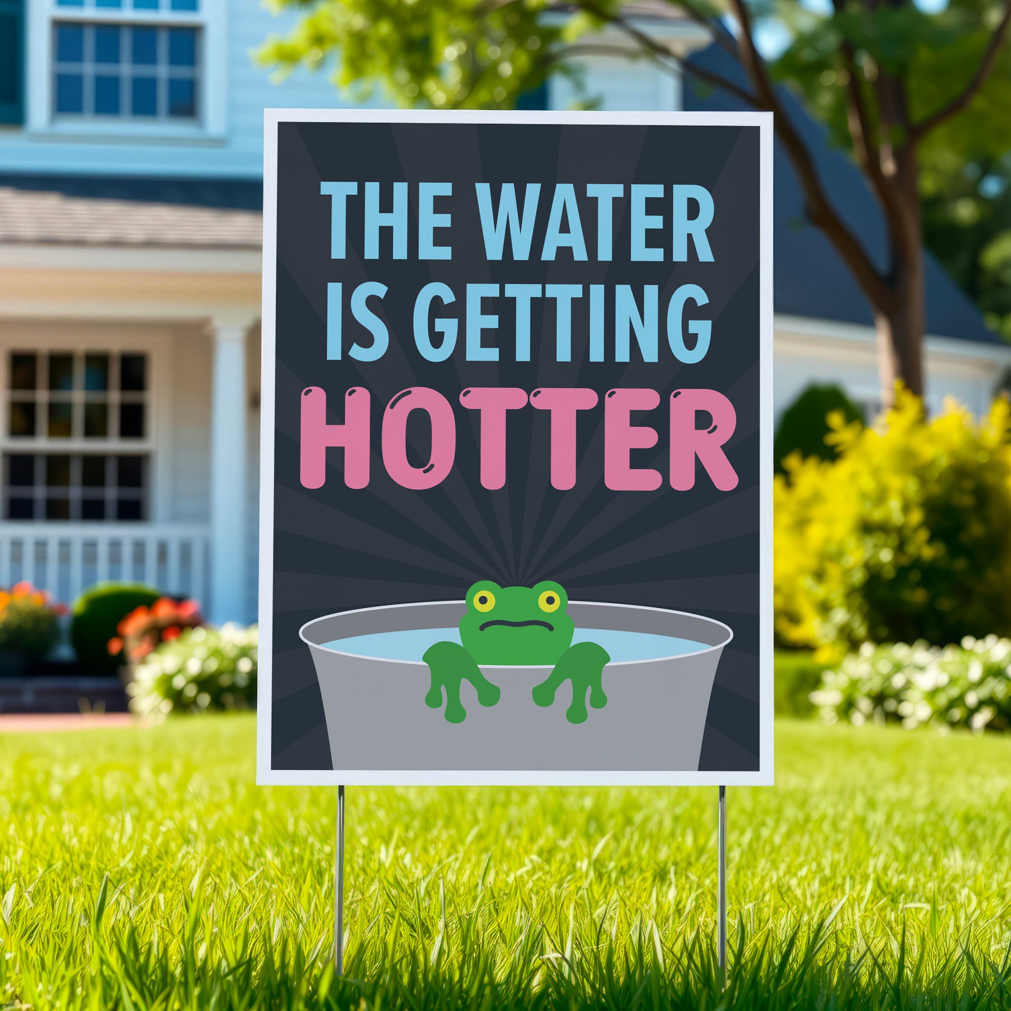 Anti-trump yard sign with bold text in blue and pink that says "The water is getting hotter" above a cartoon illustration of a panicked frog in a pot of water, planted in a green lawn.