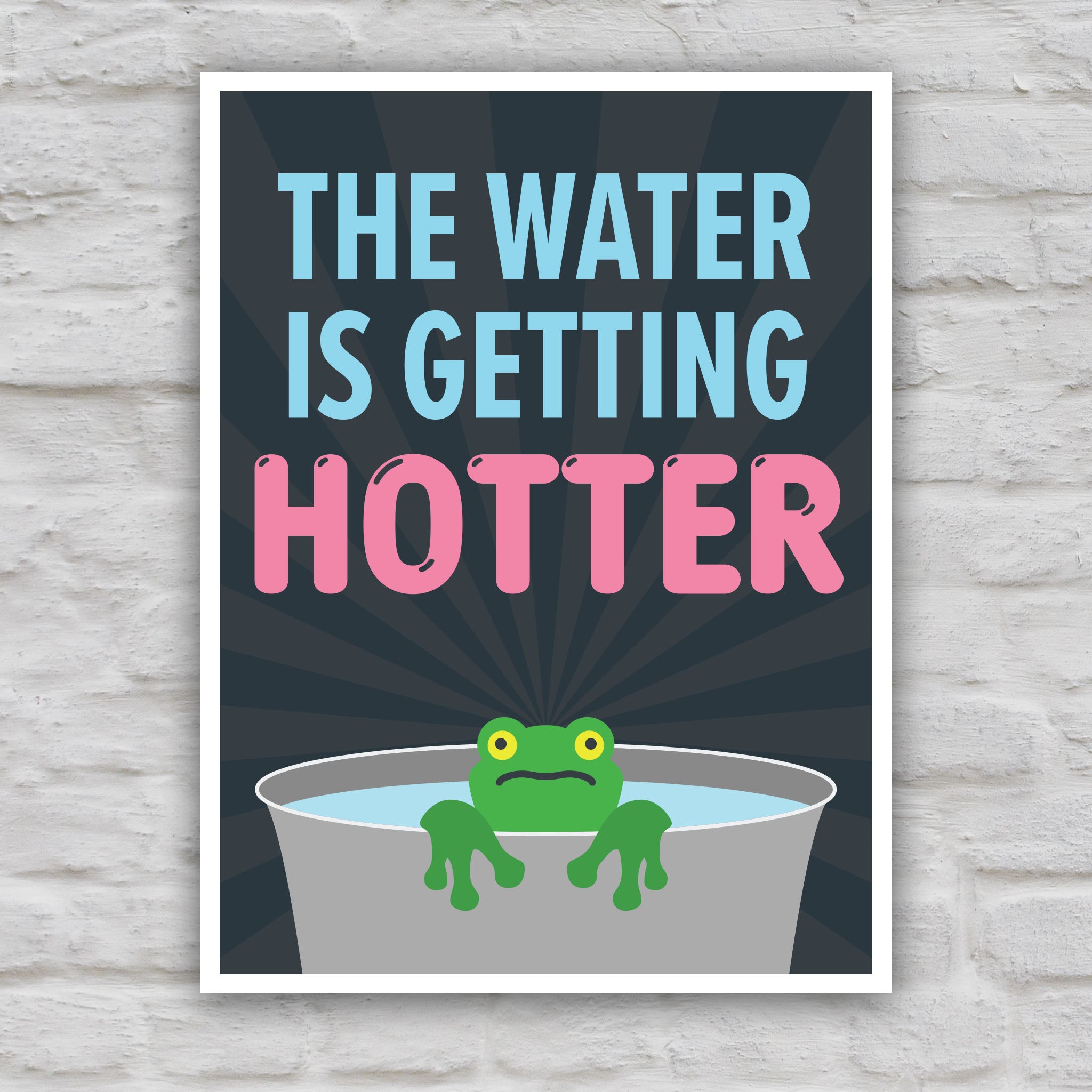 Color version of anti-trump protest sign with bold text that says "The water is getting hotter" above a cartoon illustration of a panicked frog in a pot of water.