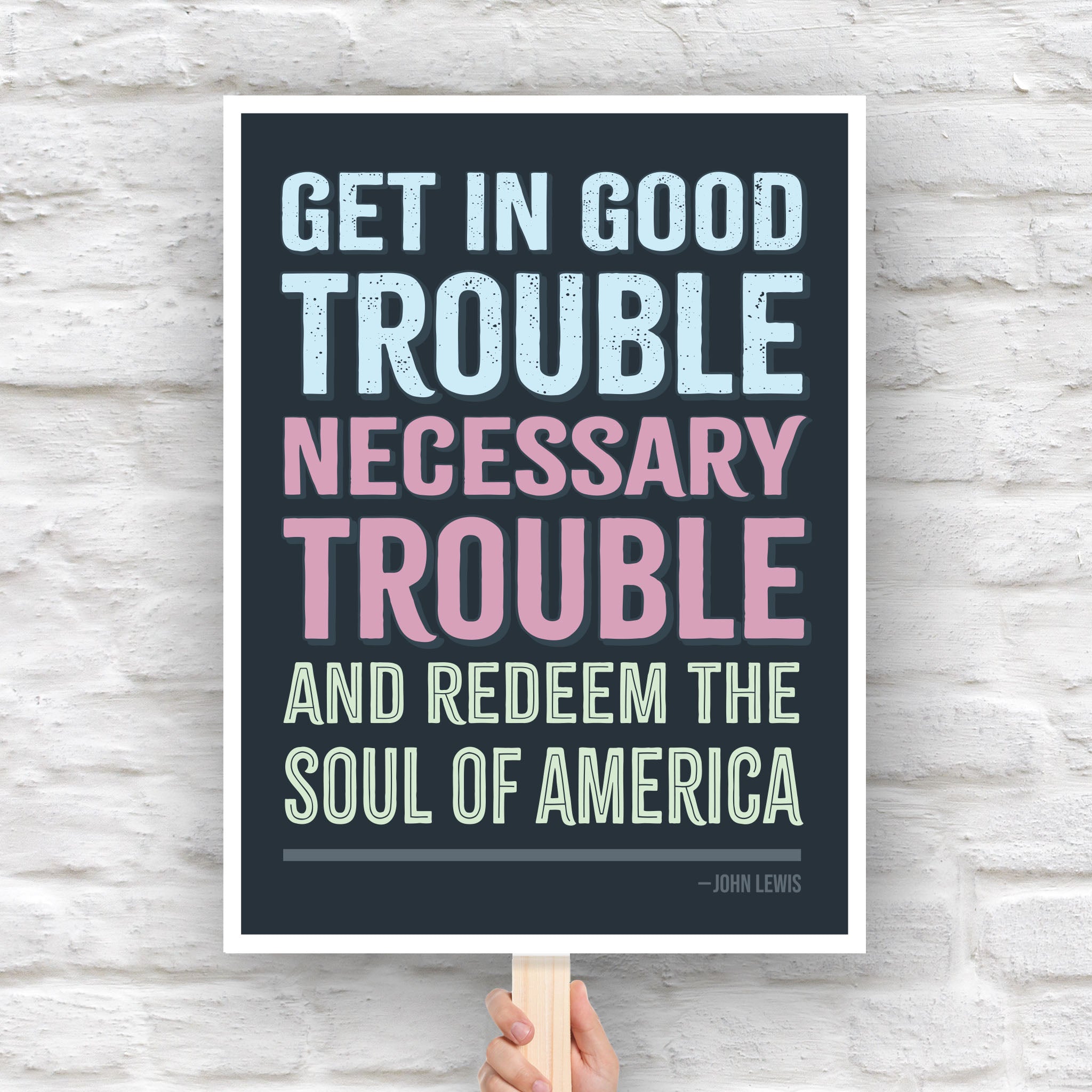 Protest sign with a dark background featuring the quote "Get in Good Trouble, Necessary Trouble, and Redeem the Soul of America" in large, bold, colorful text. The quote is attributed to John Lewis.