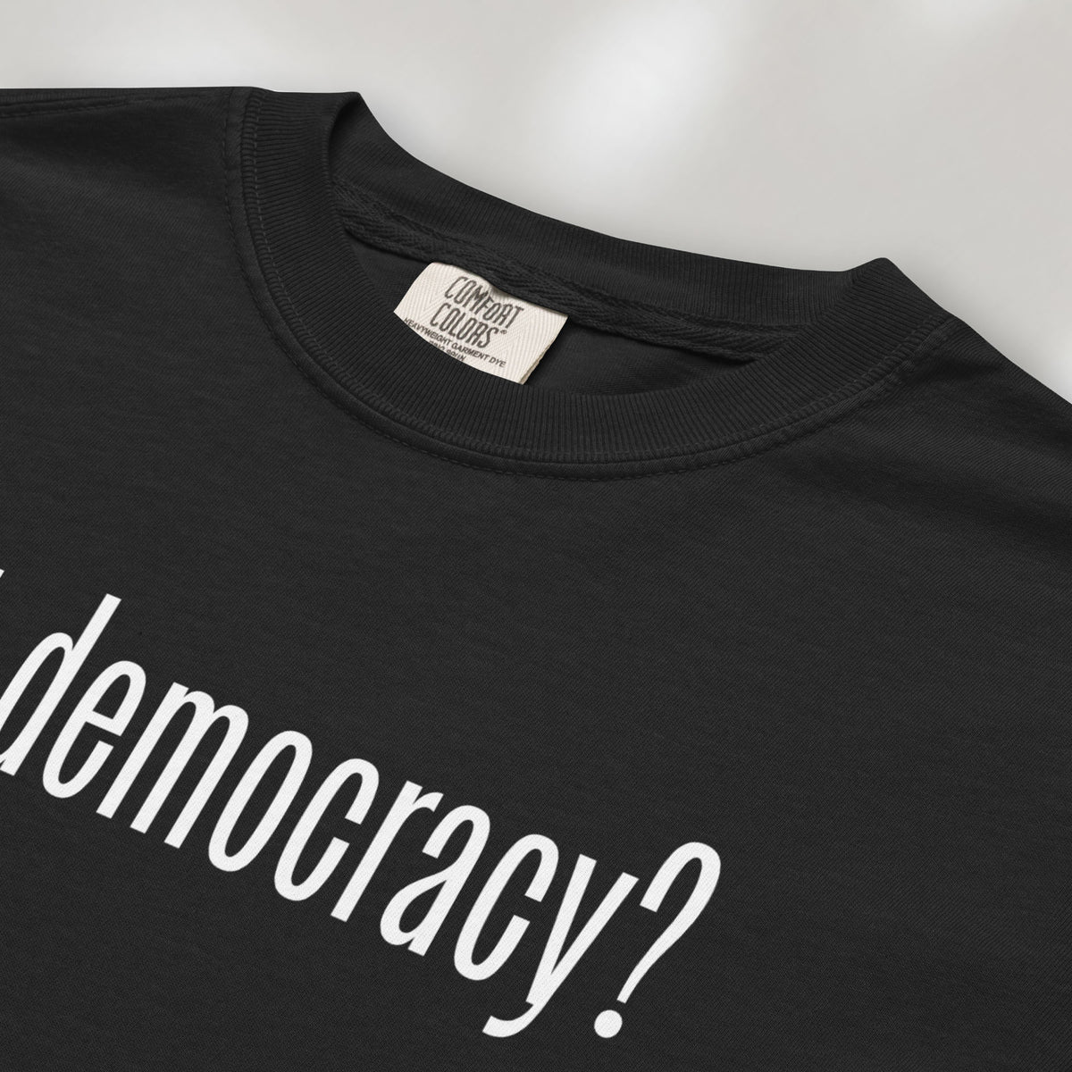 Closeup detail of black t-shirt with white text reading “got democracy?” in minimalist font, styled like the classic “got milk?” design. 