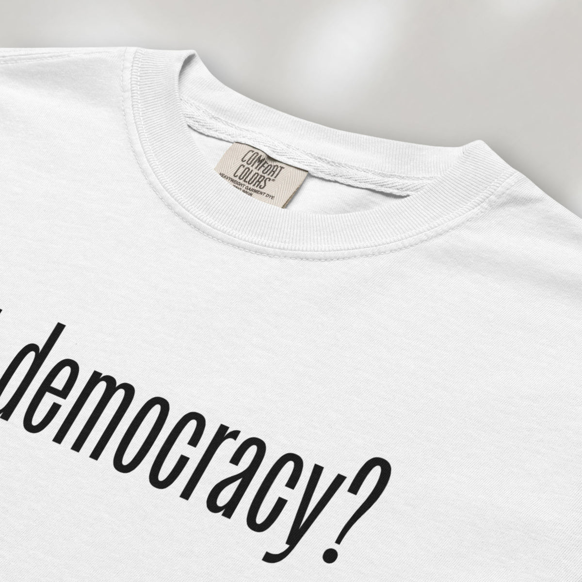 Closeup detail of white t-shirt with white text reading “got democracy?” in minimalist font, styled like the classic “got milk?” design. 