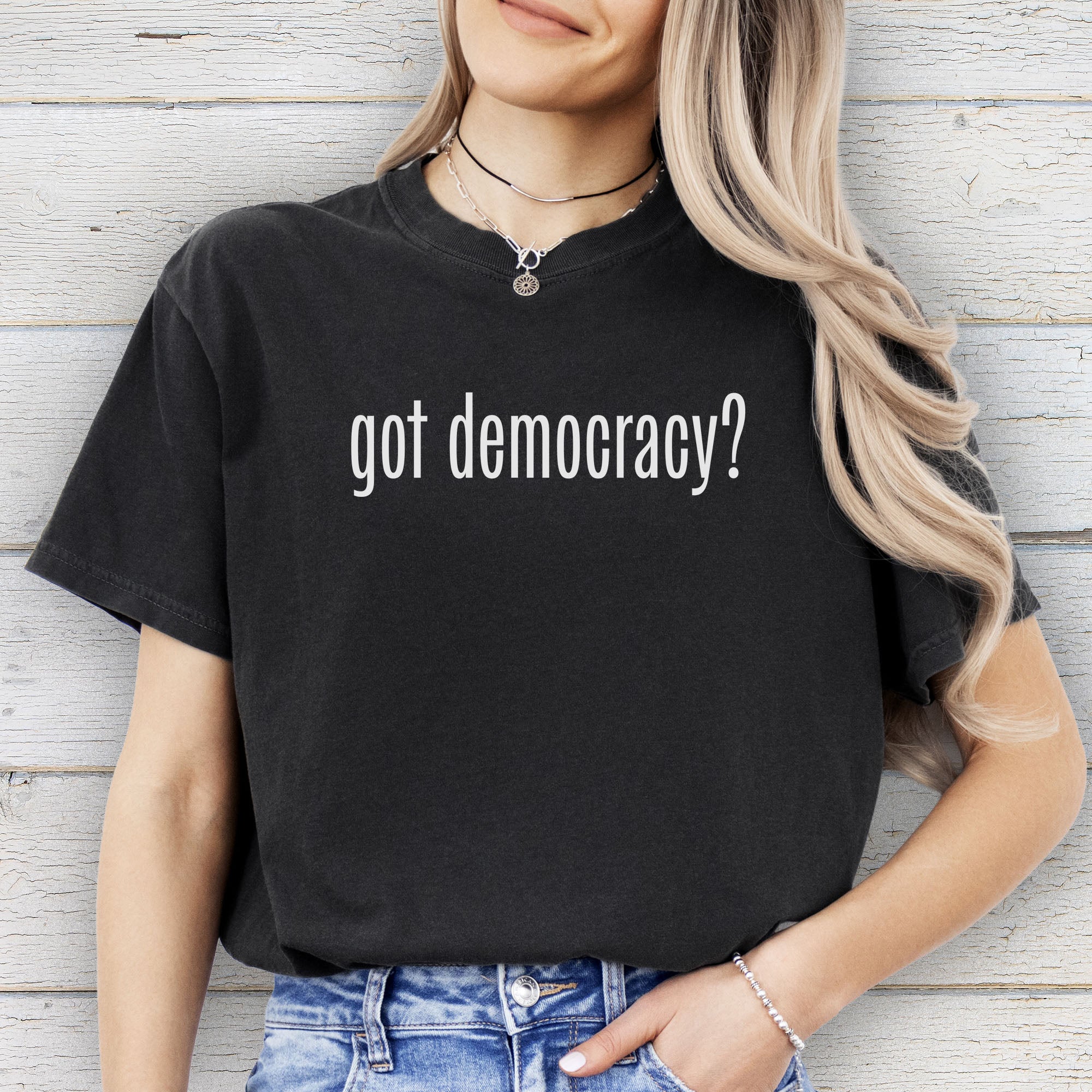 Female model wearing black t-shirt with white text reading “got democracy?” in minimalist font, styled like the classic “got milk?” design.