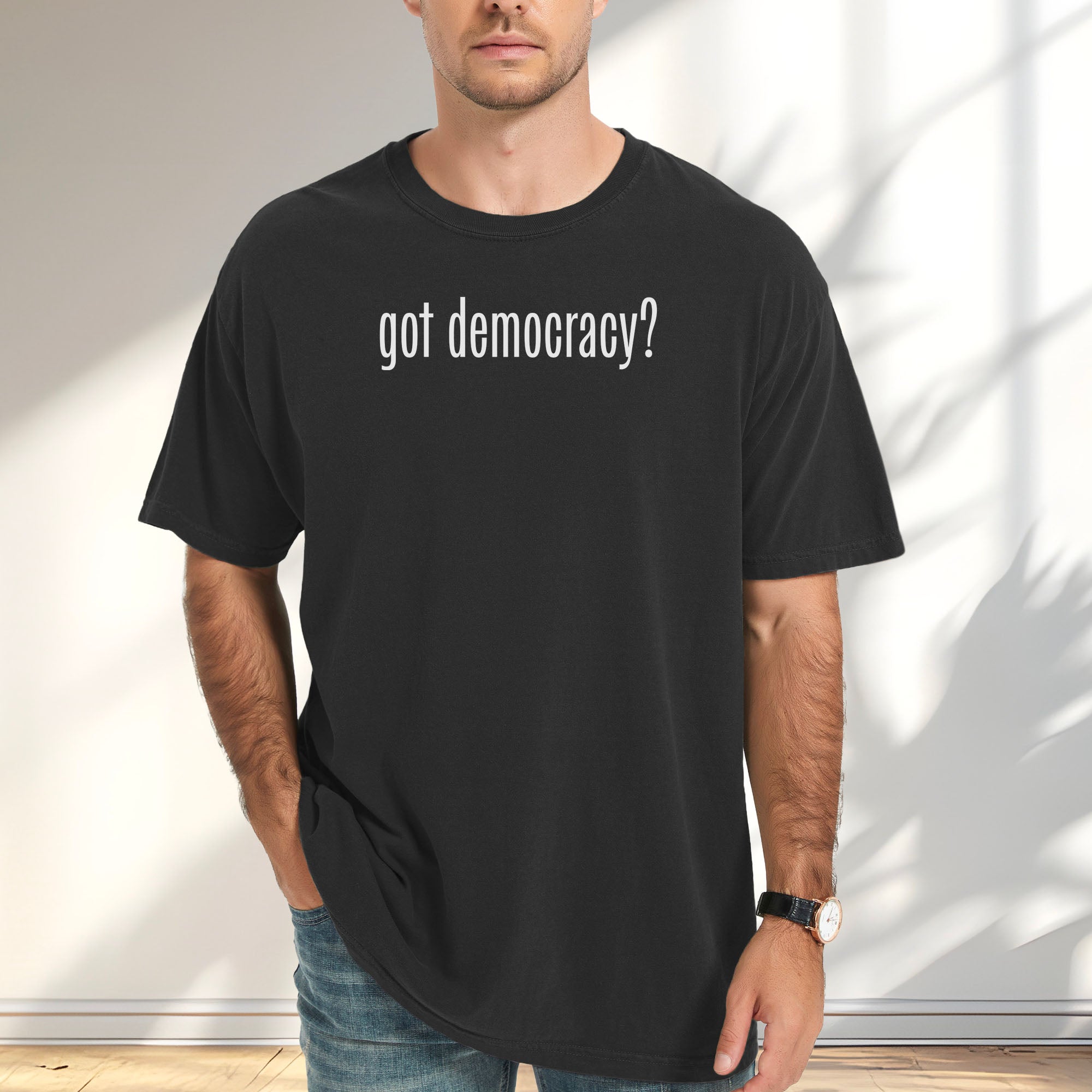 Male model wearing black t-shirt with white text reading “got democracy?” in minimalist font, styled like the classic “got milk?” campaign design.