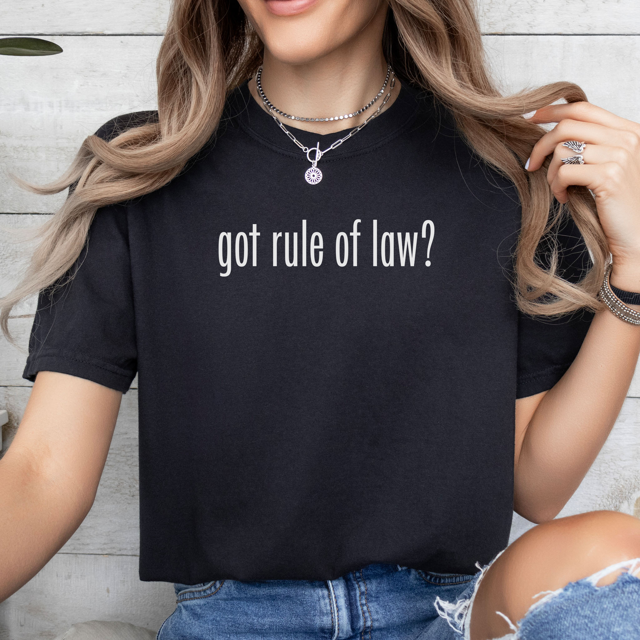 Female model wearing black t-shirt with white text reading “got rule of law?” in minimalist font, styled like the classic “got milk?” design.