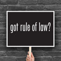 Anti-Trump protest sign with black background and bold white text that says “got rule of law?” in the style of the “got milk?” campaign.