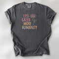 Pepper t-shirt featuring the phrase “Less Greed More Humanity” in friendly typography with a simple yellow flower illustration.