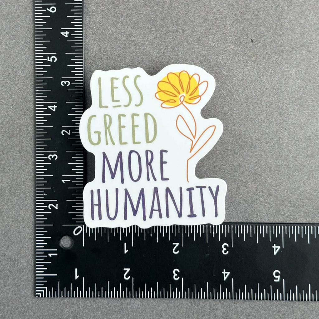 Less Greed More Humanity matte vinyl die-cut sticker with a minimalist yellow flower illustration, with ruler showing the approximate sticker size of 3 inches by 3 inches.