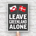 Protest sign reading “Leave Greenland Alone” with Greenland and Denmark flags, opposing Trump’s imperial threats.