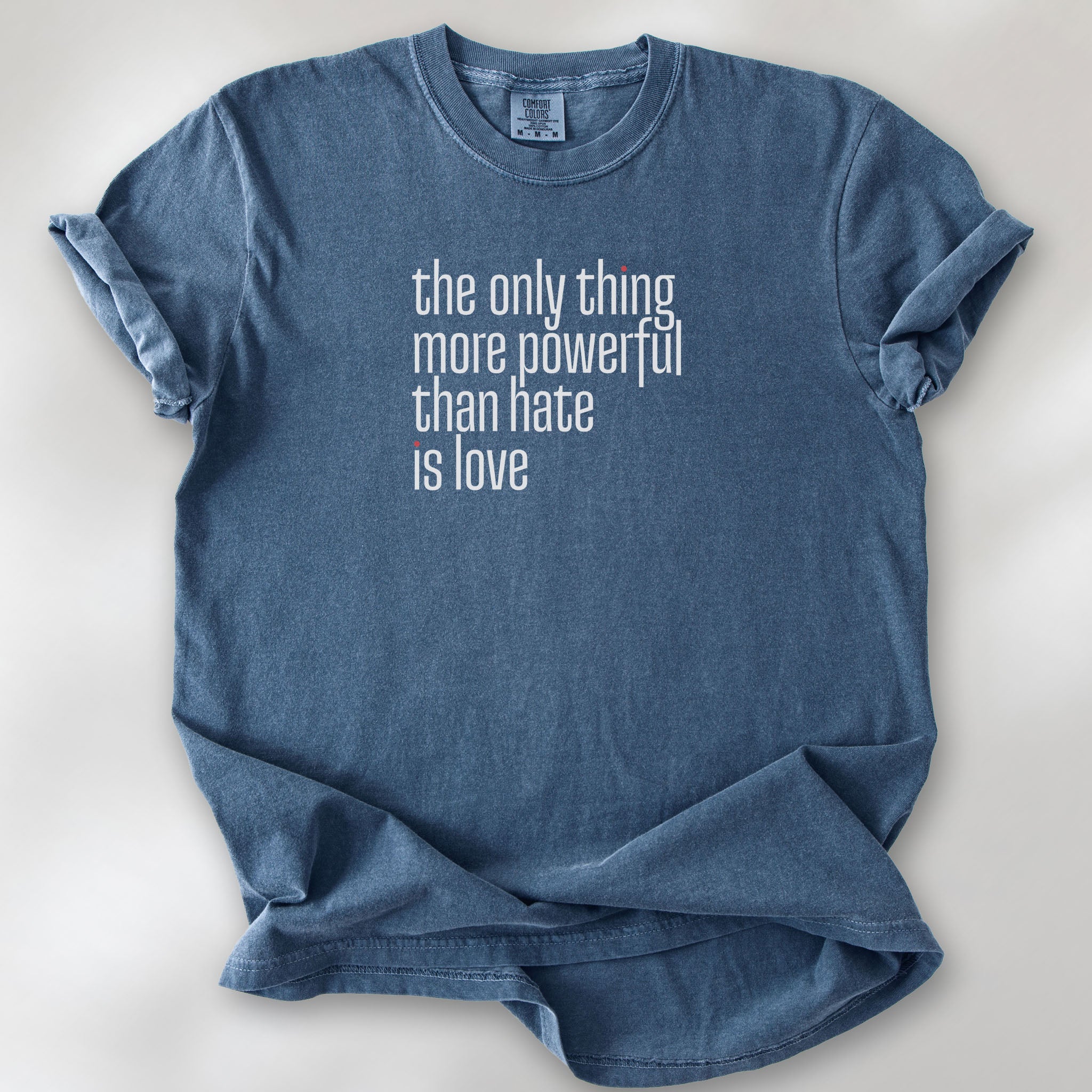 Denim t-shirt with a stylized text block reading “the only thing more powerful than hate is love."