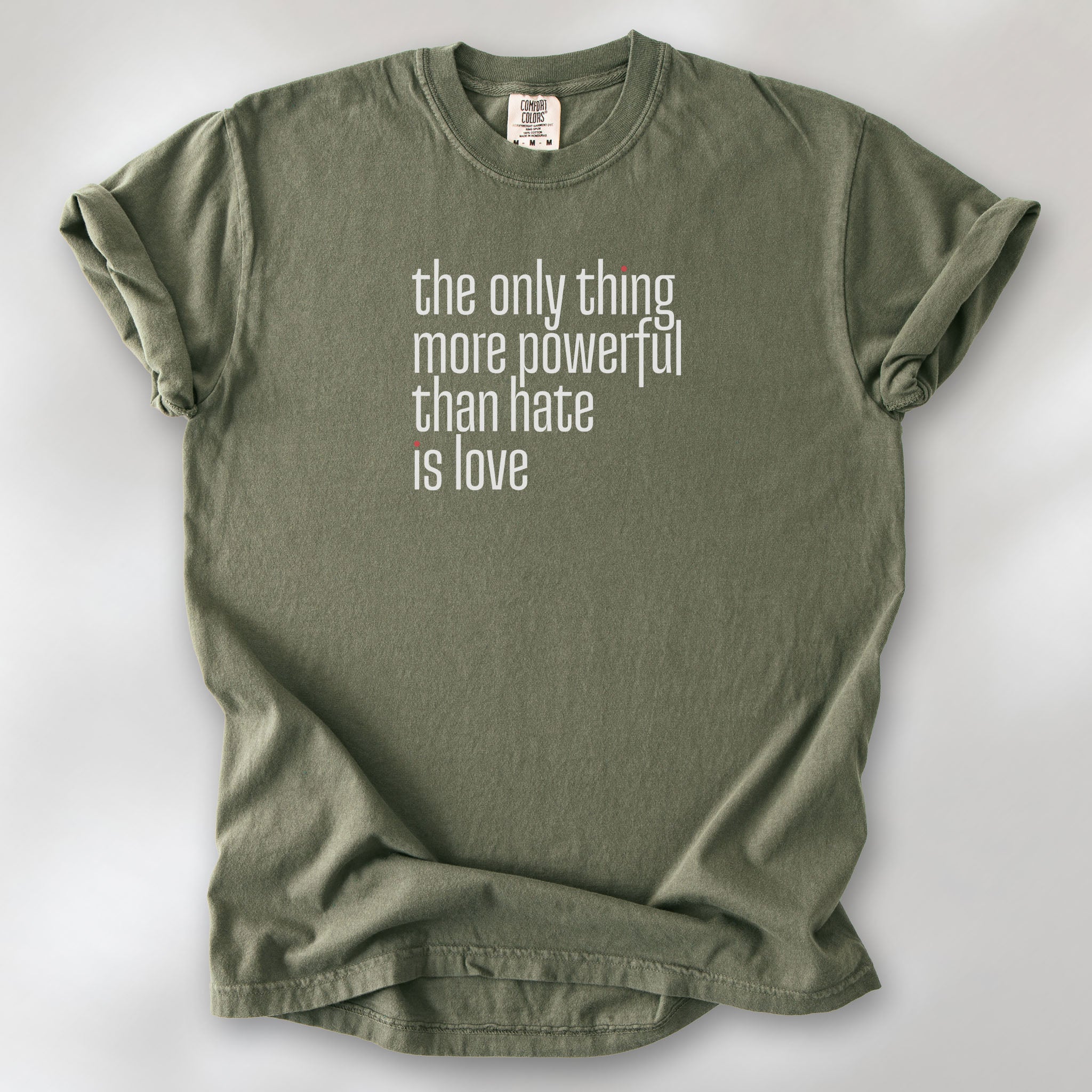 Sage t-shirt with a stylized text block reading “the only thing more powerful than hate is love."