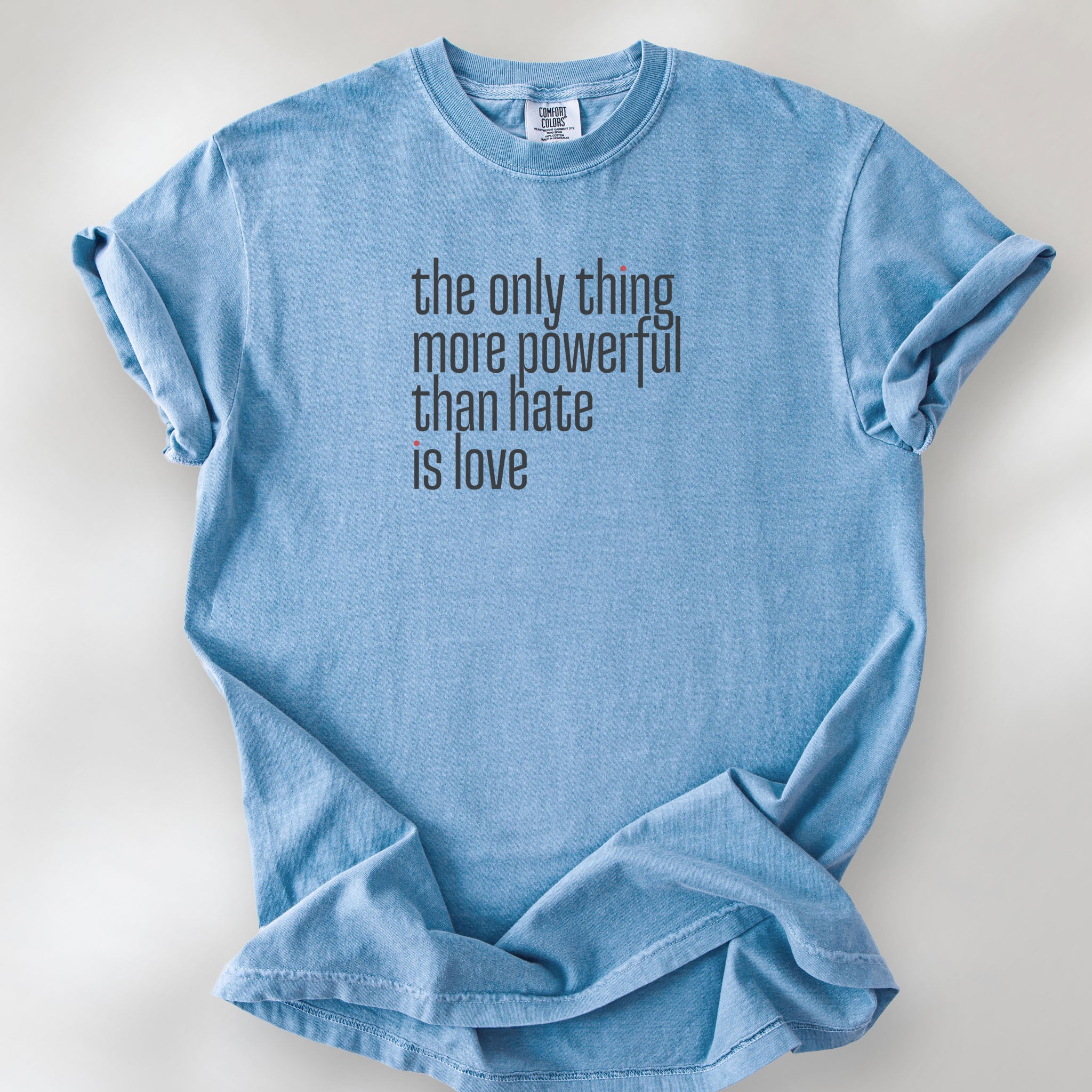 Washed denim t-shirt with a stylized text block reading “the only thing more powerful than hate is love."