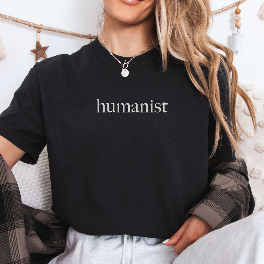 Female model wearing black Comfort Colors t-shirt with minimalist serif text reading “humanist”.