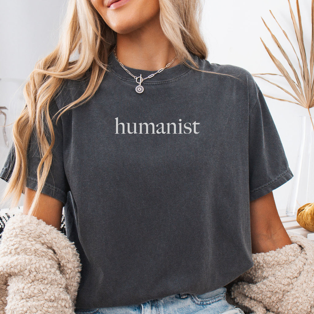 Female model wearing pepper Comfort Colors t-shirt with minimalist serif text reading “humanist”.