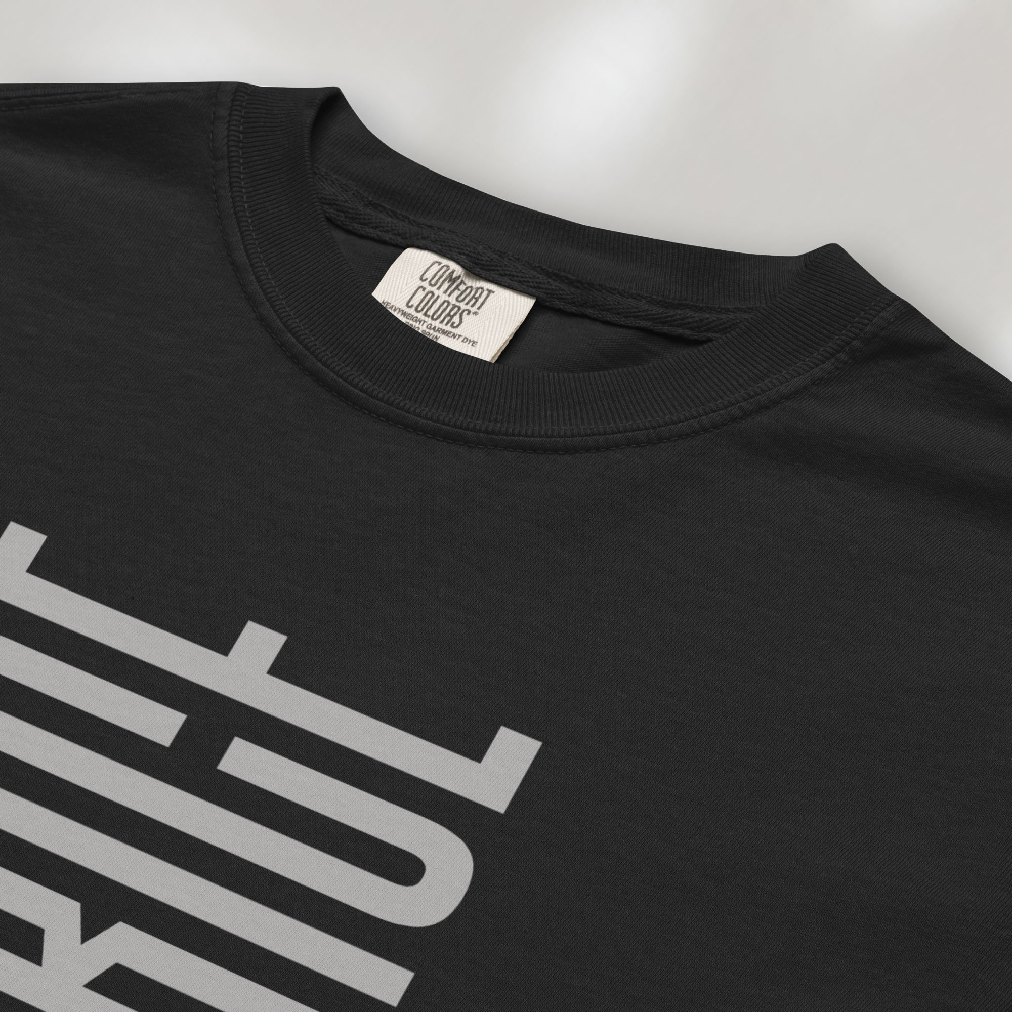 Closeup detail of black t-shirt with minimalist geometric design that subtly spells “Fuck ICE” using stacked bars and negative space, hidden protest message shirt.